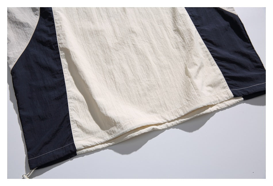 Close-up of the pullover's ivory lower front, navy side panels, and stitched hem.