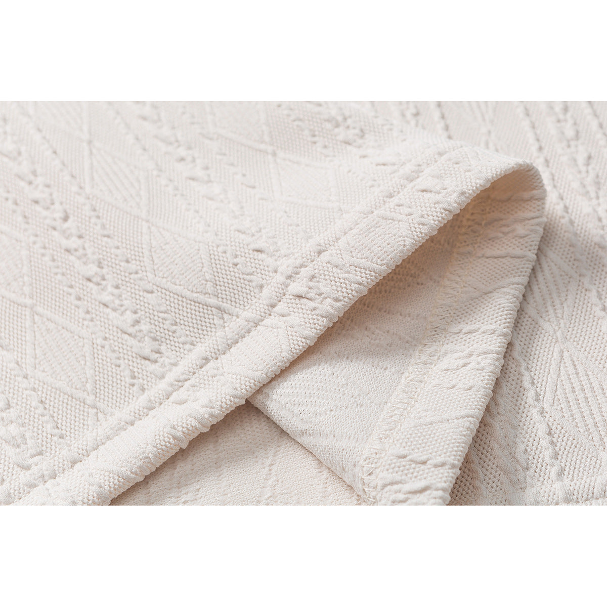 Close-up of the cream polo's textured knit, with a folded edge revealing the inner surface.