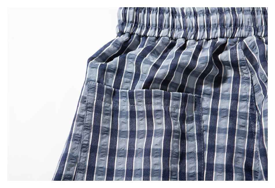 Close-up of the elastic waistband and stitched front pocket on blue-gray striped shorts.