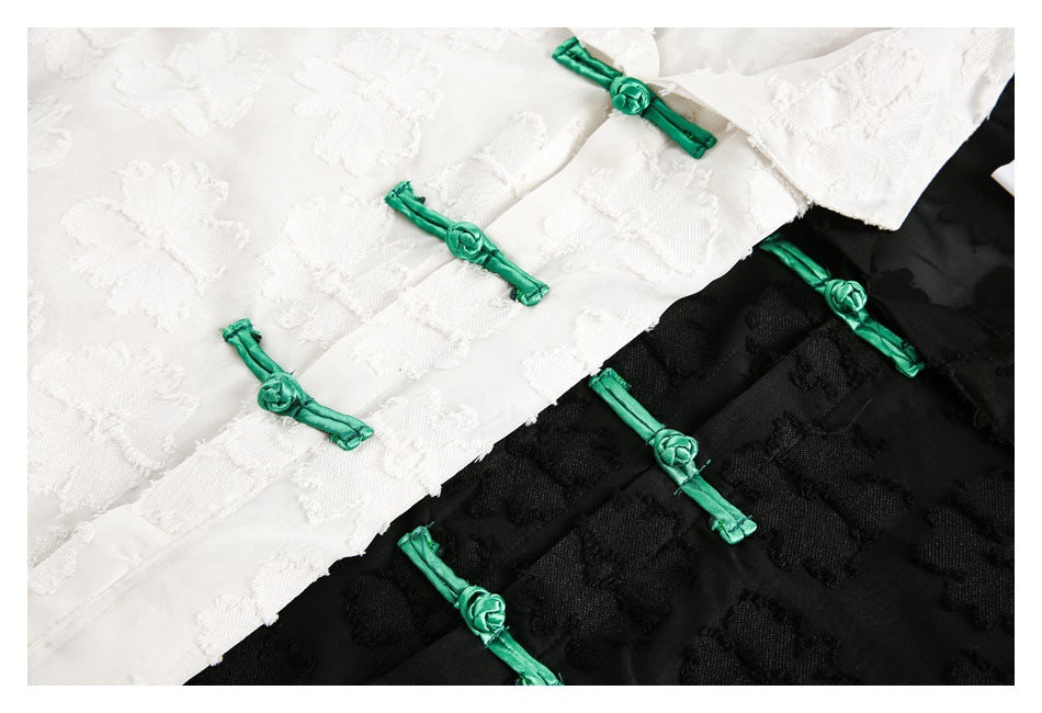 Close-up of green frog closures on white and black shirts with raised floral patterns.