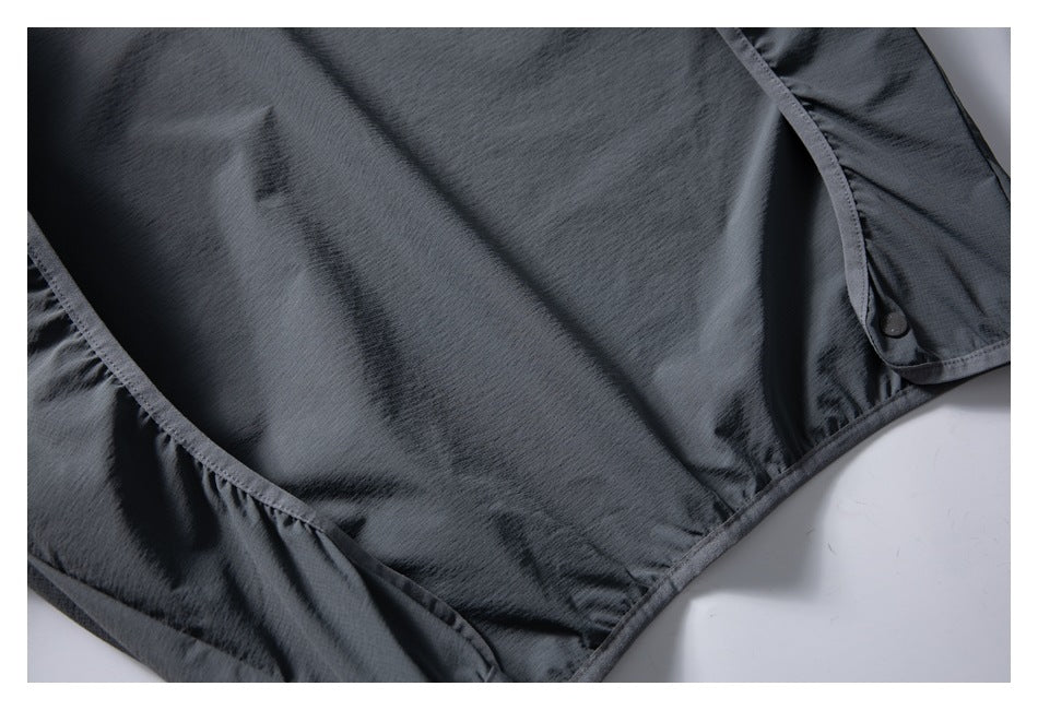 Close-up of the vest's dark fabric, bound seams, lower edge, and a snap fastener.