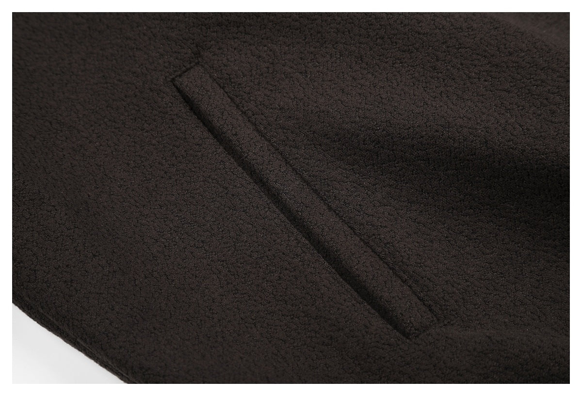 Close-up of a diagonal pocket opening on dark brown textured fabric.