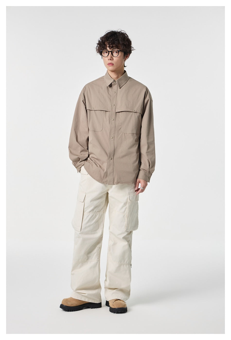 Full-length model wearing a taupe button-front shirt with flap chest pockets and off-white cargo trousers.