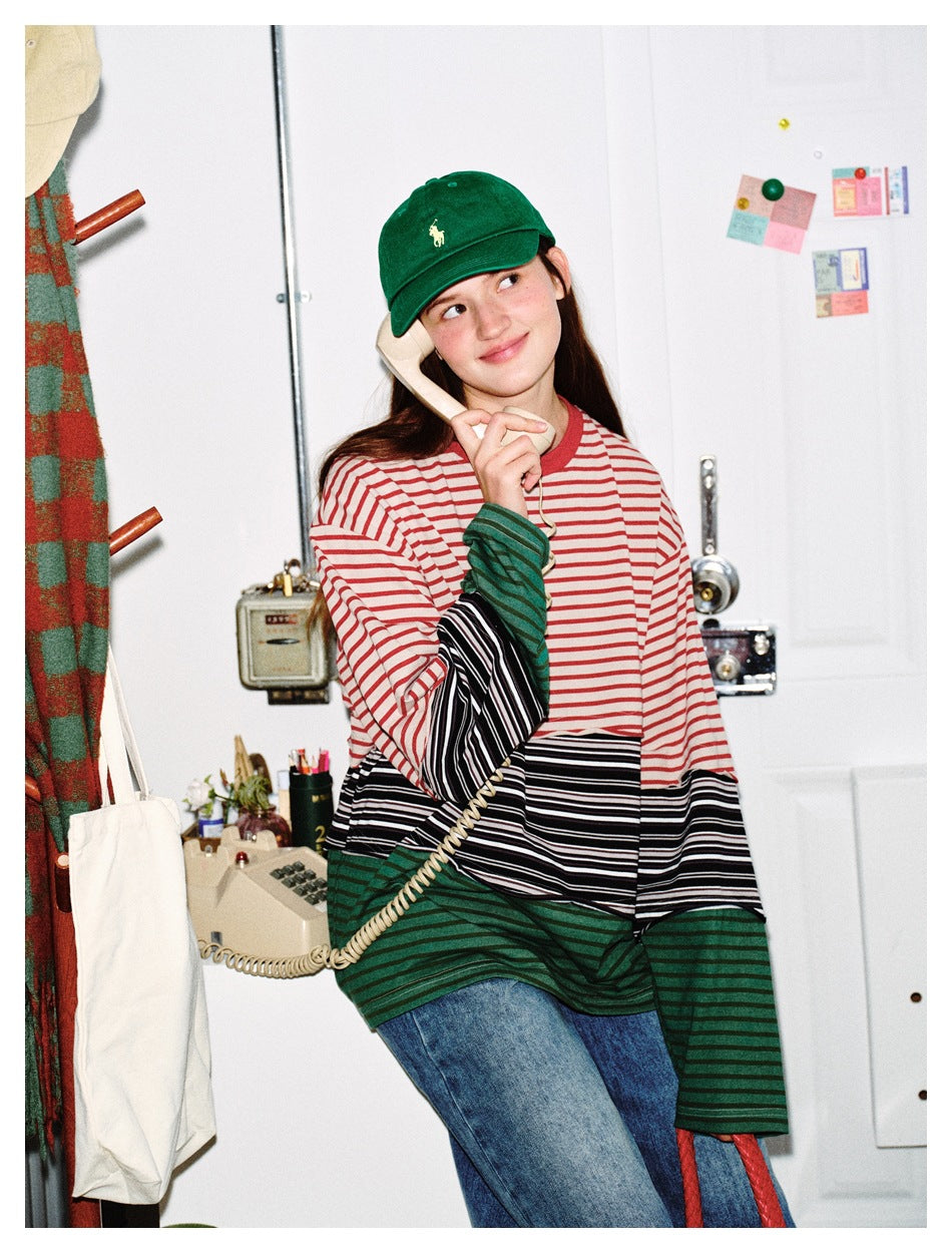 Closer view of a model wearing a red, cream, black, and green striped color-block shirt.