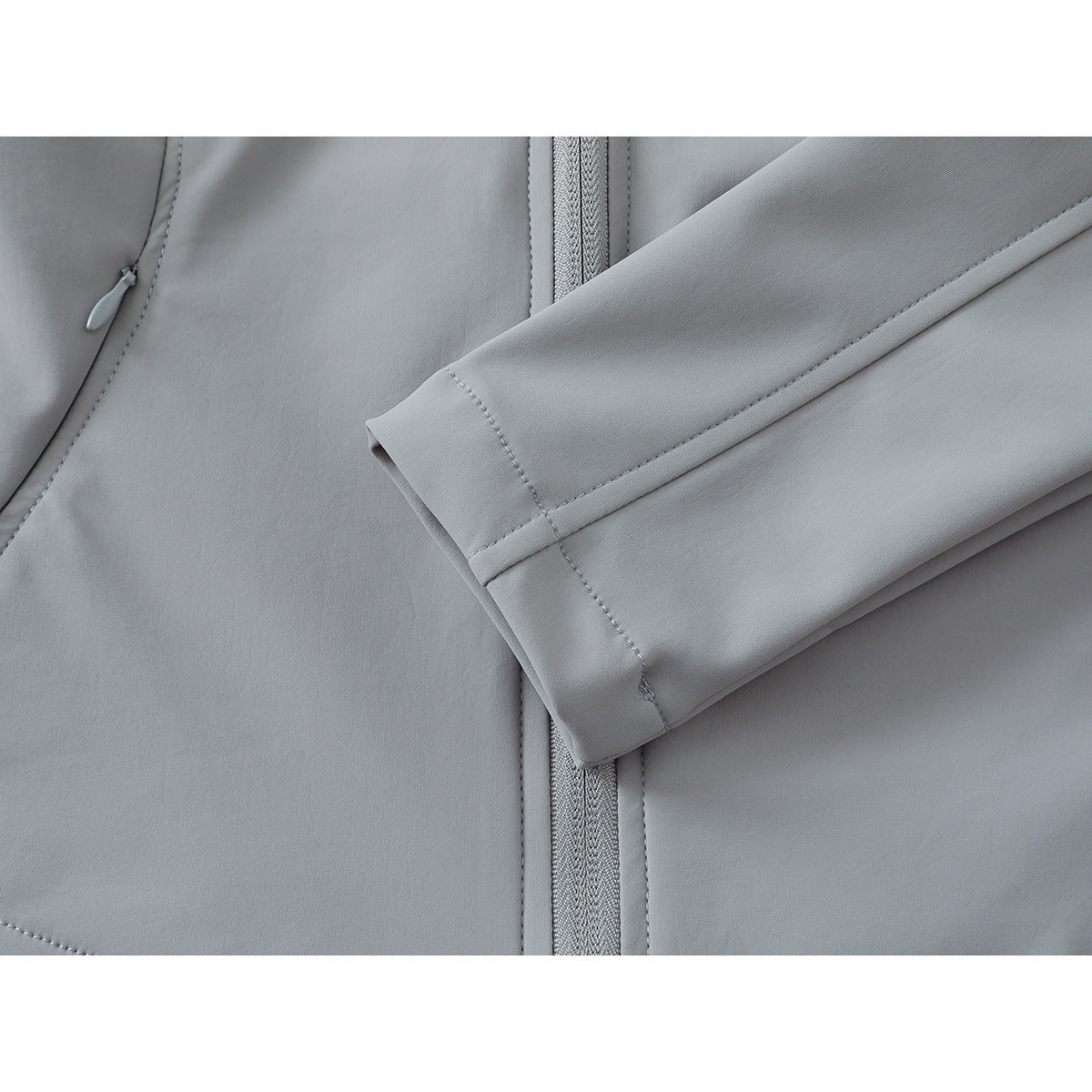 Close-up of a light gray jacket sleeve cuff crossing the front, with a small pocket zipper visible.
