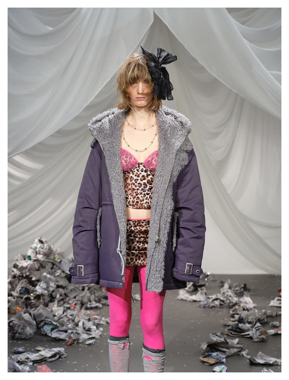 Front view of a model wearing an open plum parka with a broad shaggy gray collar and buckle details.