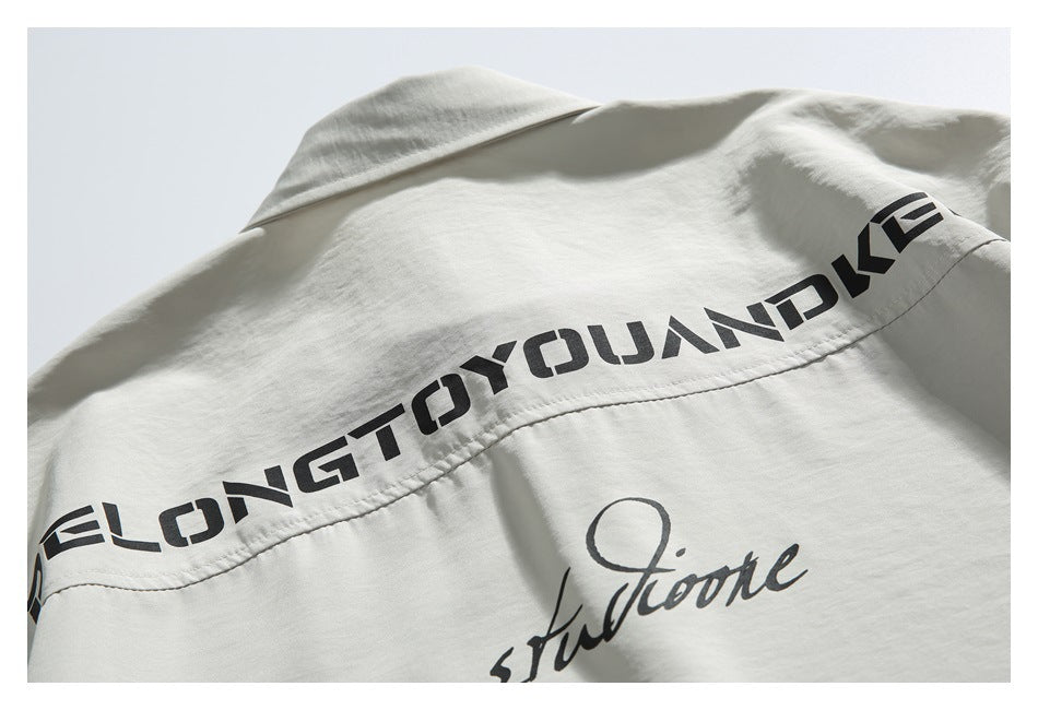 Close-up of an off-white shirt back with bold black lettering across the yoke and script below.