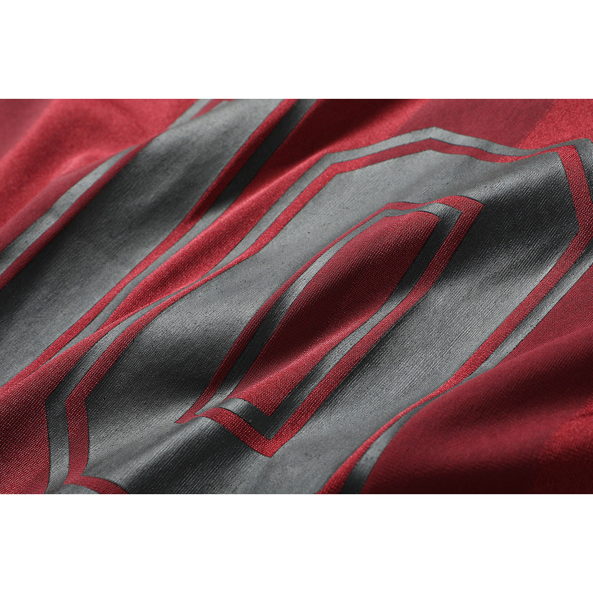 Close-up of a red shirt with a large gray and black geometric graphic outlined in red.