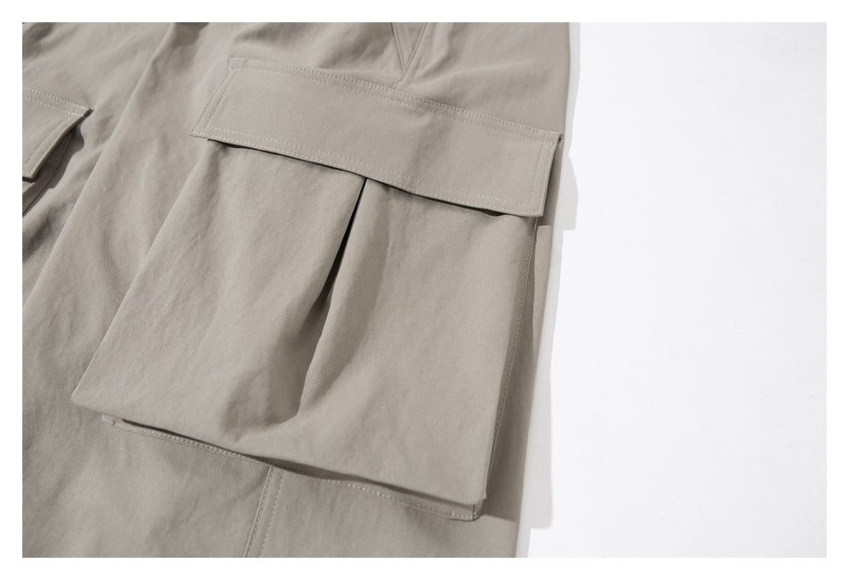 Close-up of a taupe-gray garment with a large flap cargo pocket and visible topstitching.
