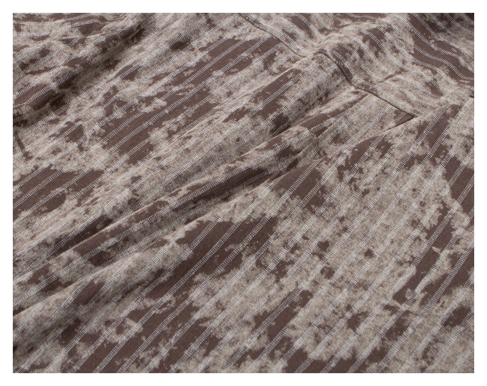 Close-up of brown and beige fabric with diagonal stripes, mottled markings, and visible folds.