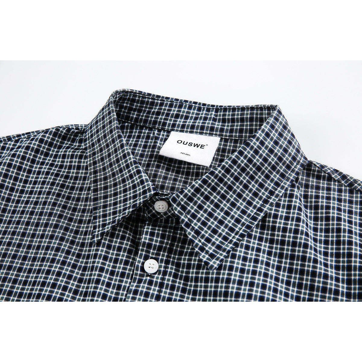 Close-up of a black checked shirt collar, white buttons, and a sewn-in OUSWE label.