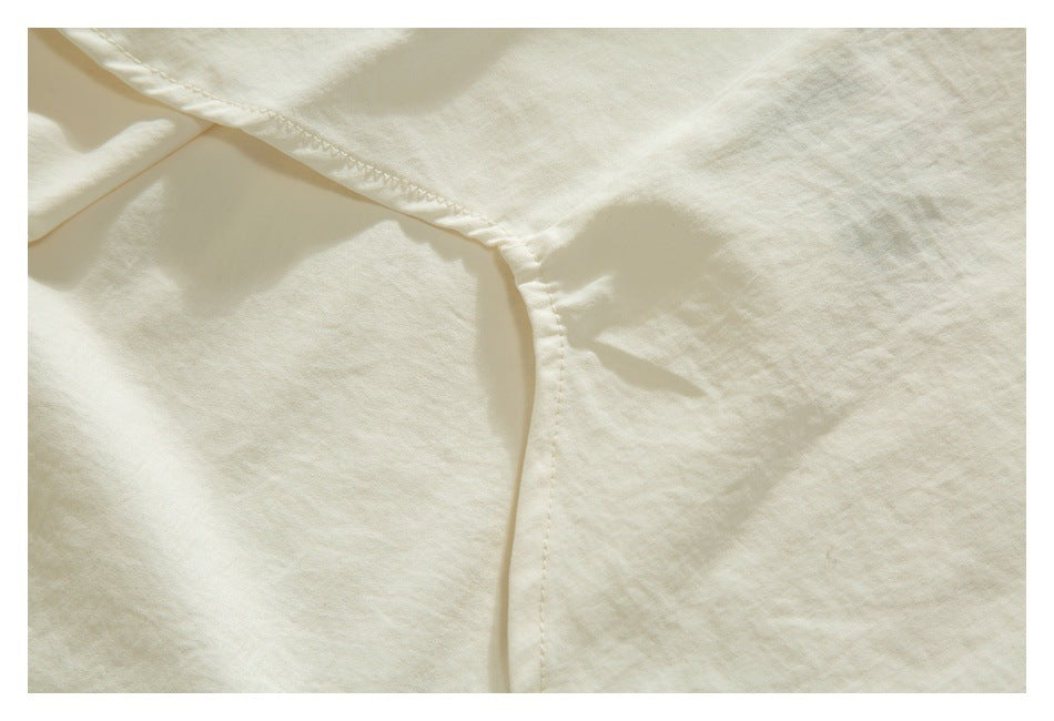 Close-up of an ivory garment seam and folded edge with visible stitching.