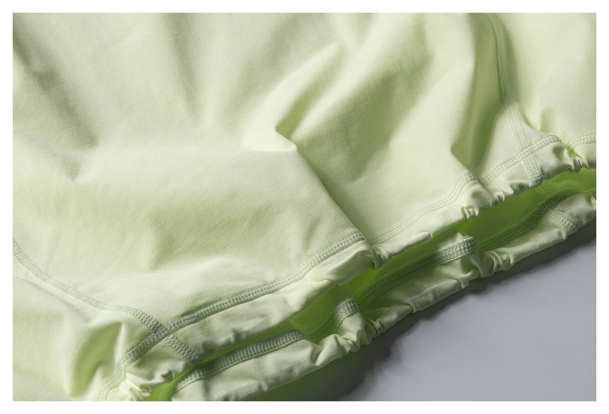 Close-up of stitching and a gathered elastic edge on pale lime fabric.