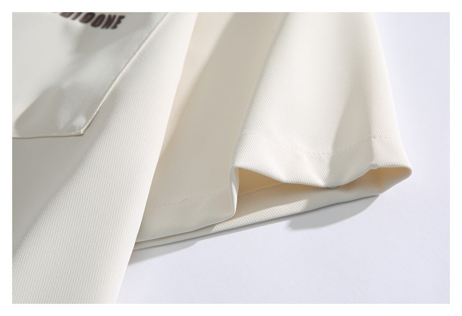 Close-up of an ivory shirt sleeve hem with a small portion of dark printed lettering visible.