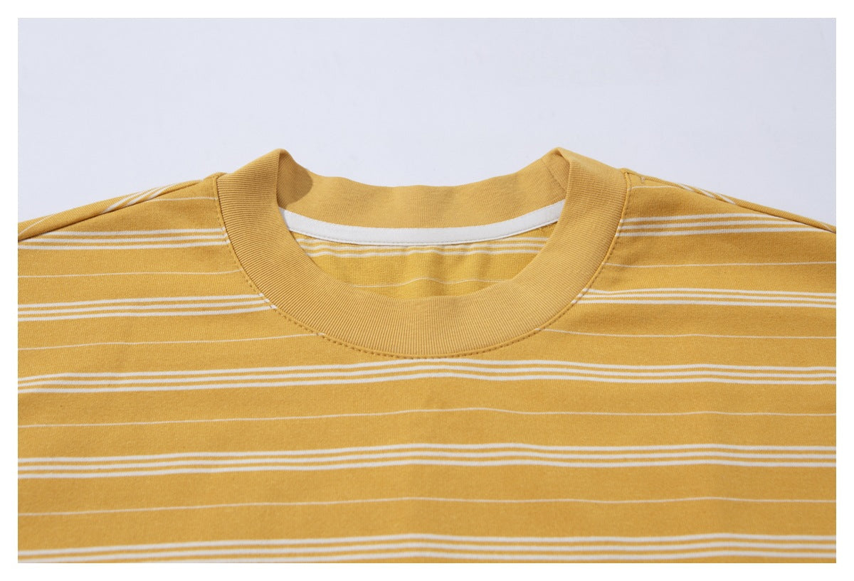 Close-up of a mustard yellow T-shirt neckline with a ribbed crew neck and thin white horizontal stripes.