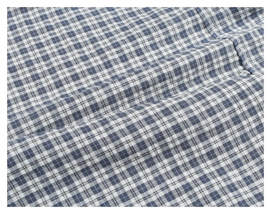 Close-up of a seam and folded fabric on a blue, gray, and white plaid shirt.