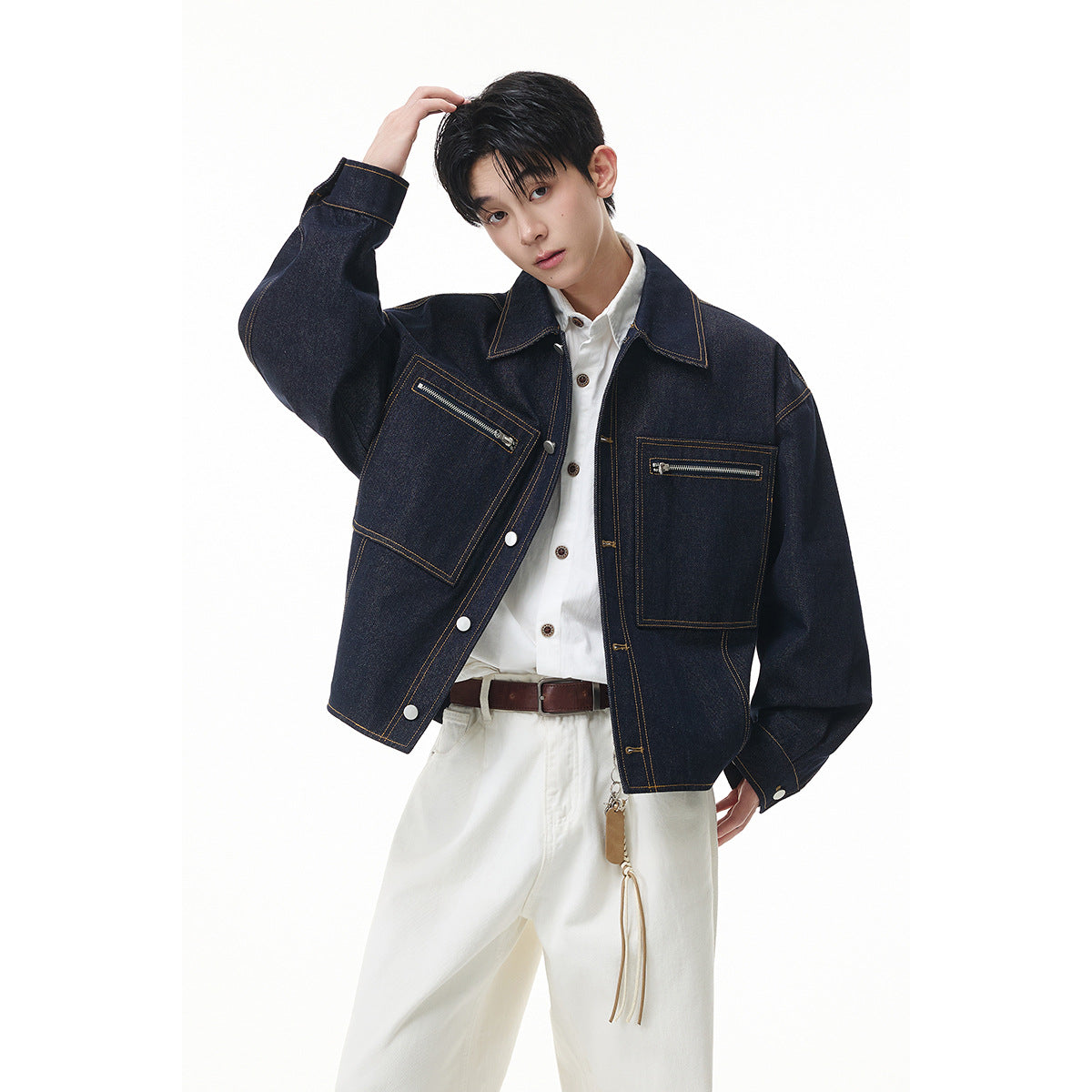 Model wearing an oversized dark indigo denim jacket with contrast stitching, two zip pockets and white trousers.