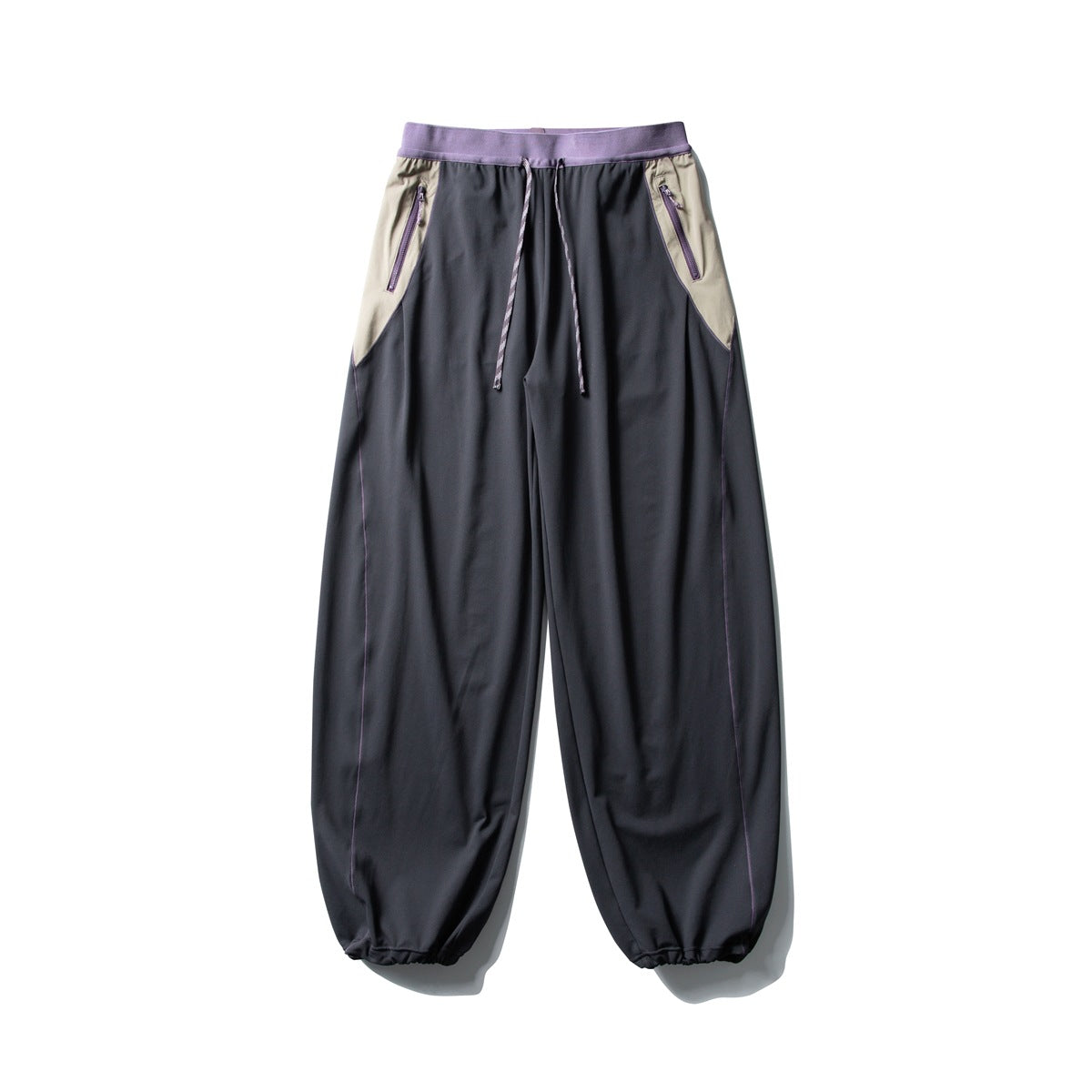 Front view of charcoal wide-leg pants with a lilac waistband, beige zip-pocket panels, and a drawstring waist.