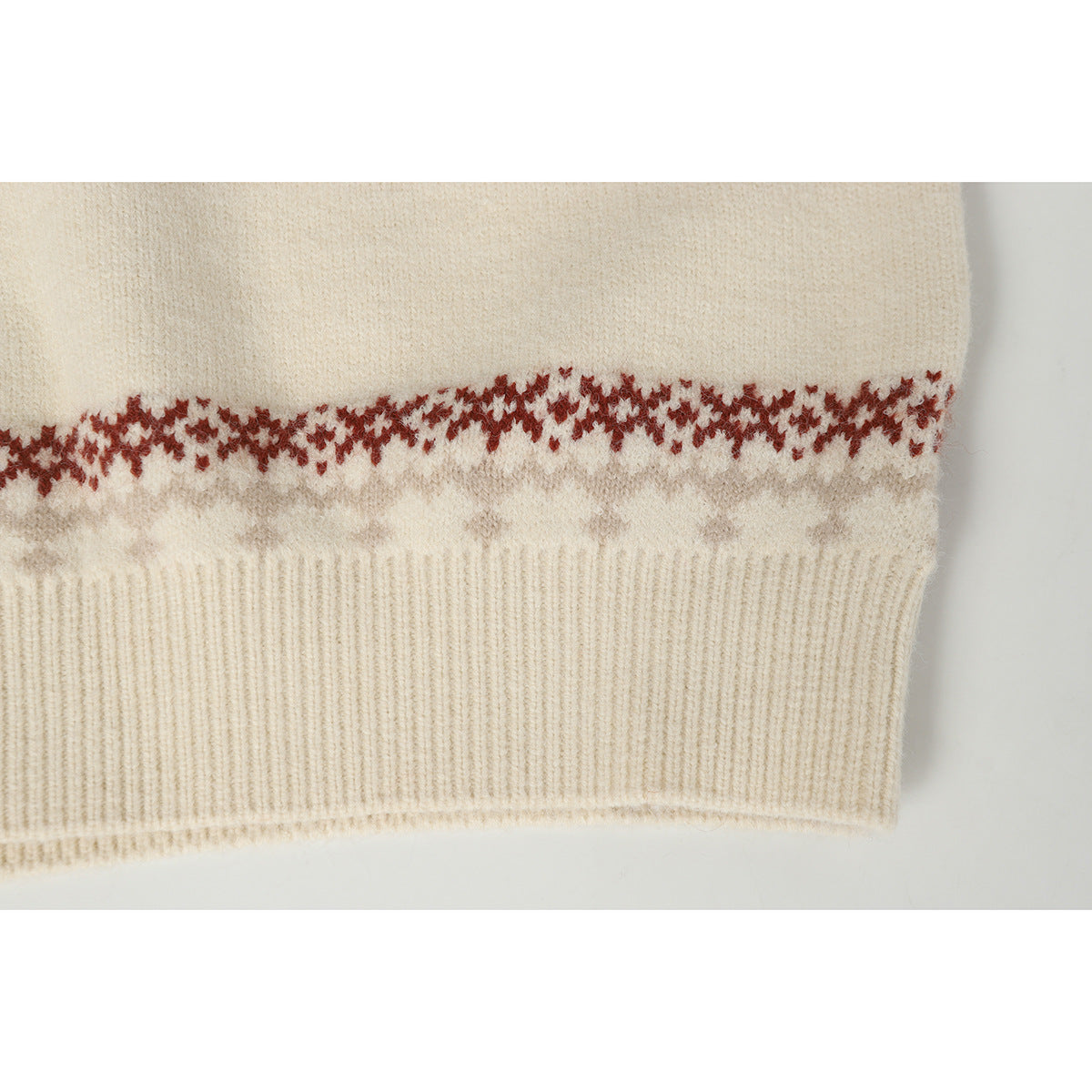 Close-up of an ivory sweater hem with ribbed trim and a rust and taupe geometric pattern band.