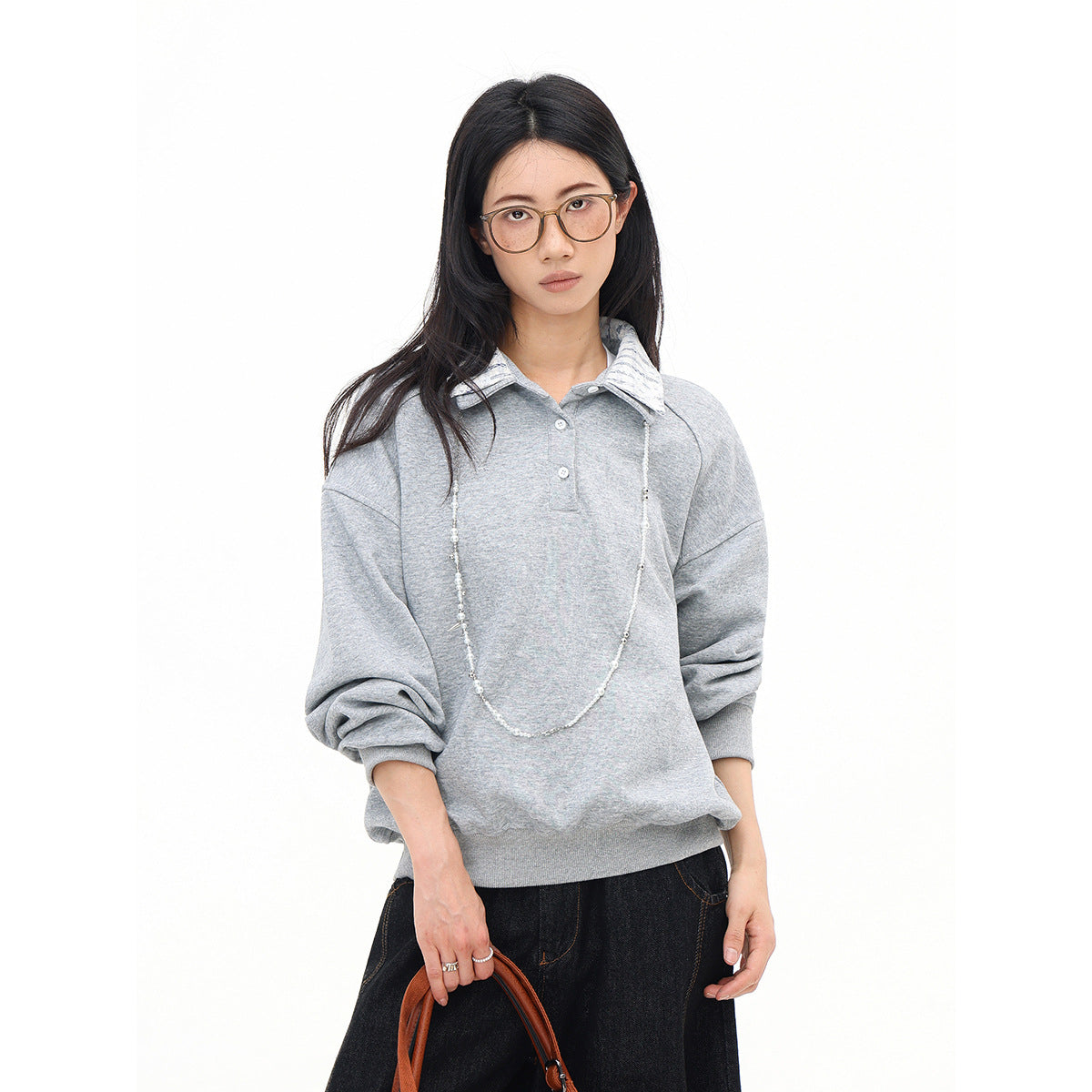 Model wearing a light gray oversized collared pullover with a striped collar and dark jeans, shown from the front.