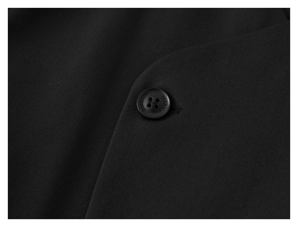 Close-up of a black jacket button and overlapping fabric panels.