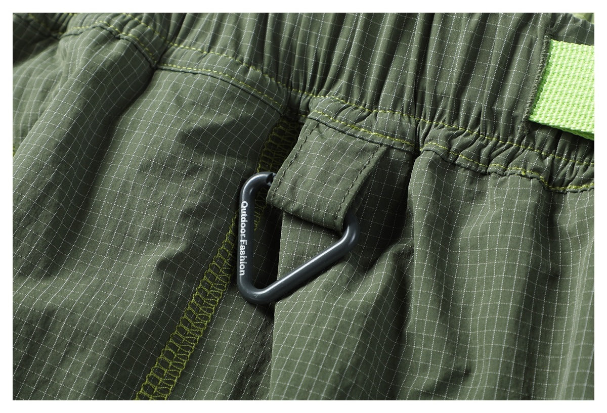 Close-up of the pants' elastic waistband, stitching and attached black plastic clip marked Outdoor Fashion.