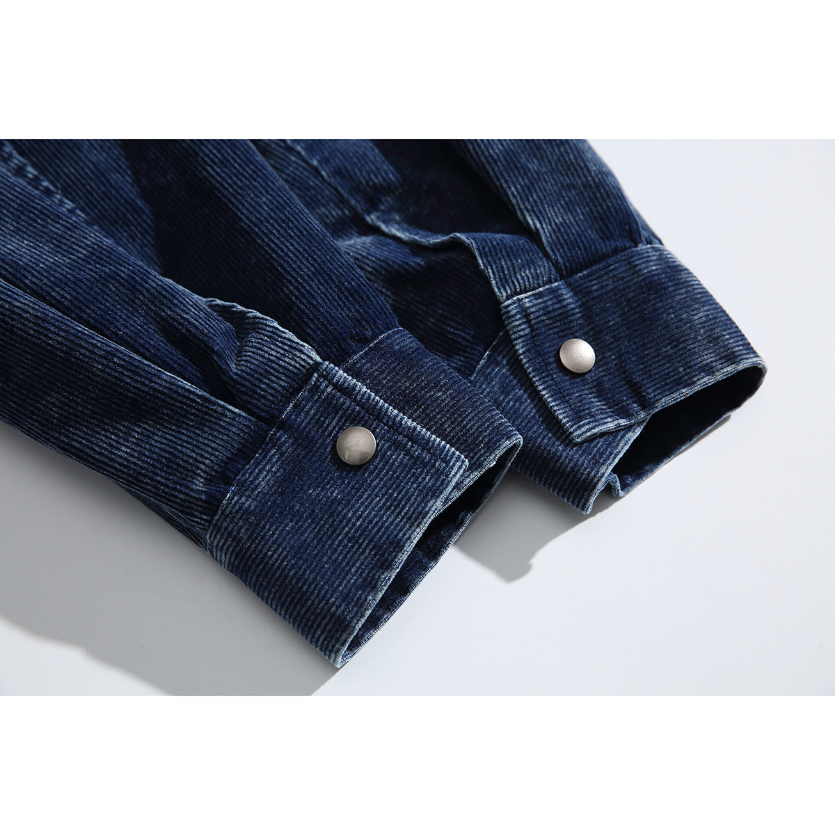 Close-up of the dark navy ribbed jacket's sleeve cuffs with silver-tone snap buttons.