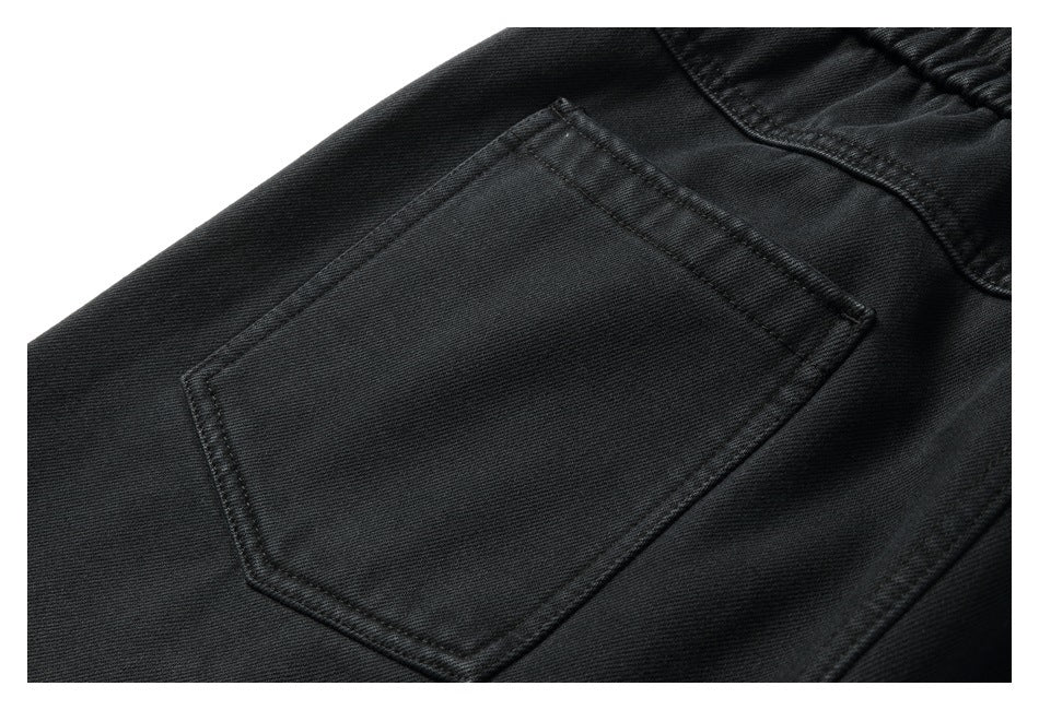 Close-up of black pants showing a stitched back pocket and waistband seam.