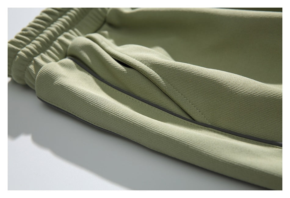 Close-up of sage green jogger pants showing an elastic cuff and dark side piping.