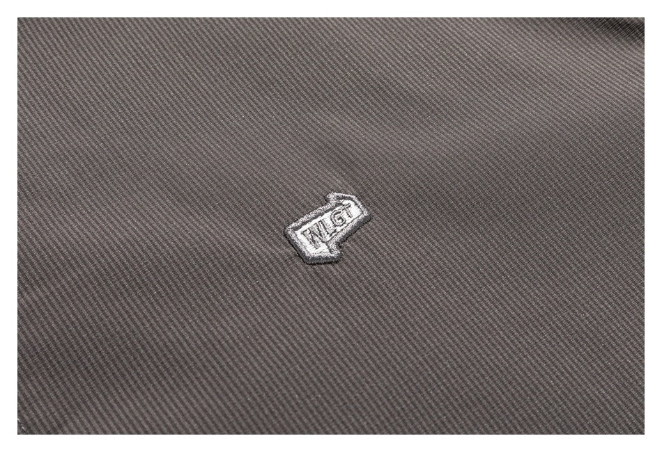 Close-up of a small embroidered emblem on the gray jacket's finely textured fabric.