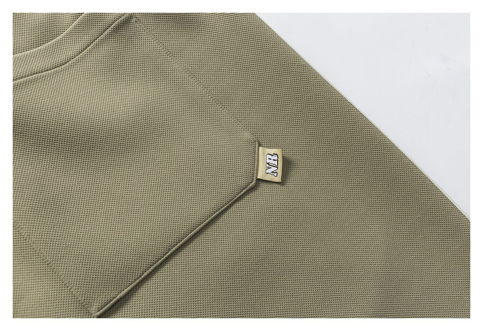 Close-up of olive-gray textured garment fabric with a small NB label.