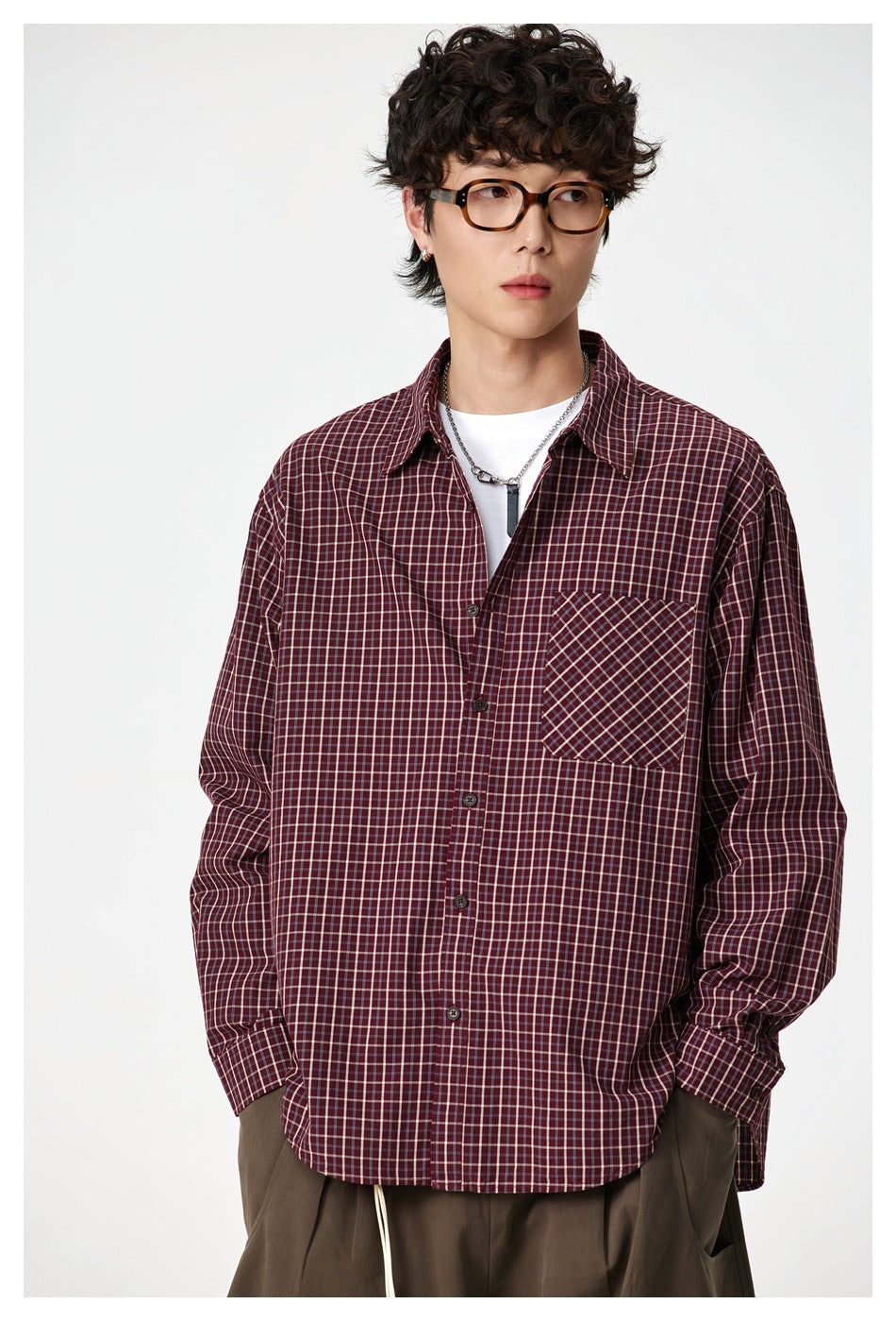 Close front view of a model wearing a burgundy check button-up shirt with a diagonal-check chest pocket.