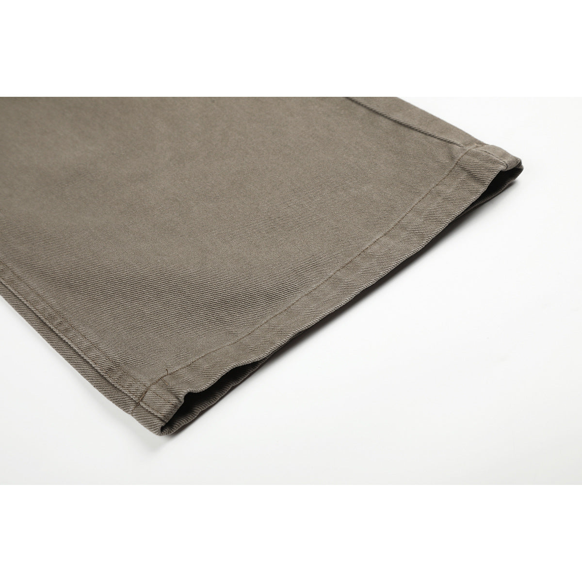 Close-up of the stitched hem on taupe-gray pants, showing the fabric texture and folded edge.