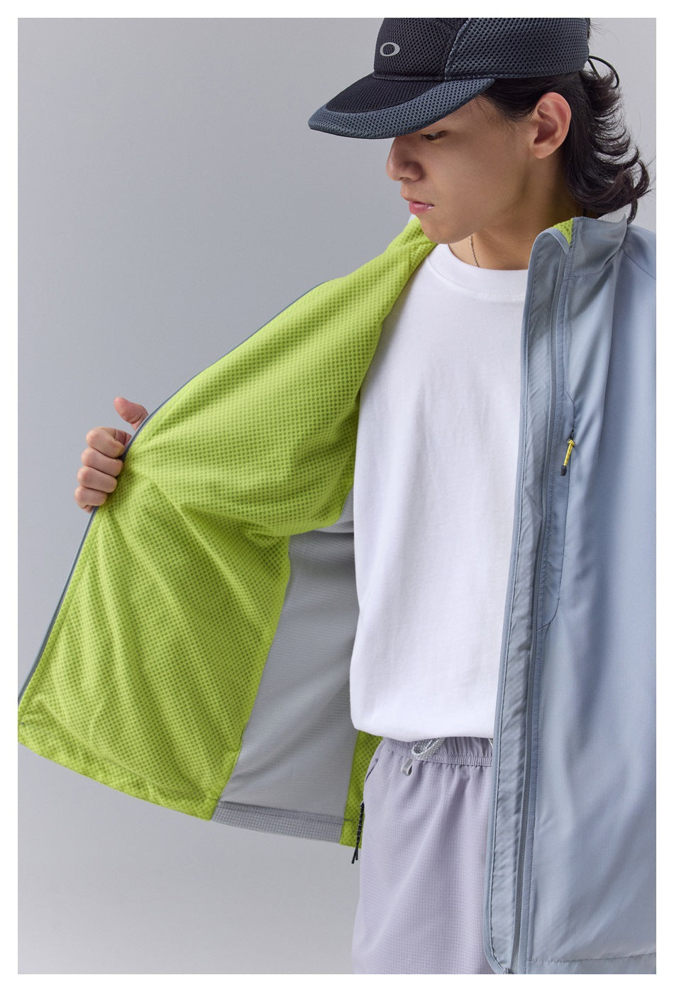 Close view of a pale blue-gray jacket opened to show its bright lime perforated lining.