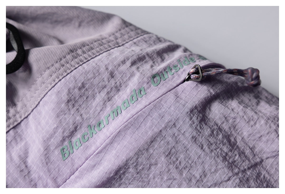 Close-up of a lavender-gray garment with raised green “Blackarmada Outside” lettering and a multicolored drawcord.