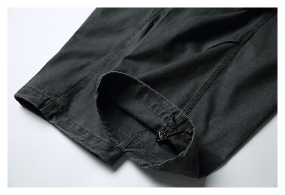 Close-up of a charcoal trouser leg hem with an adjustable strap and buckle.