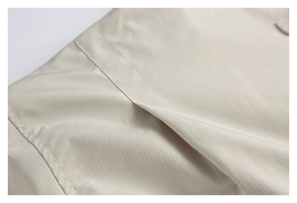 Close-up of stitching and a folded seam on the light beige jacket.