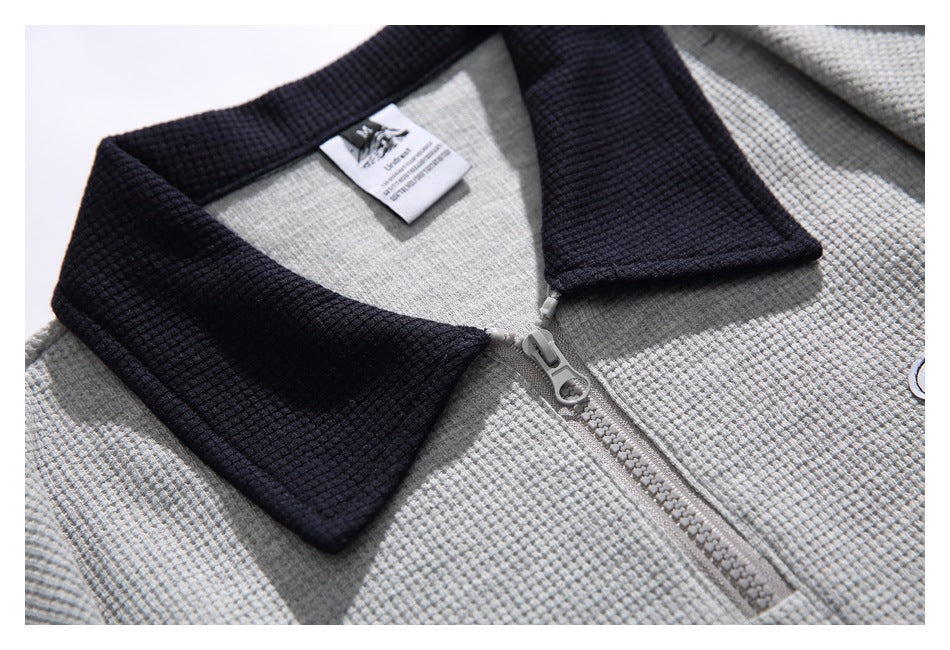 Close-up of the pullover's dark textured collar, gray zipper, and inner neck label.