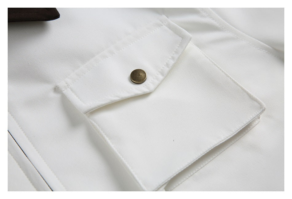 Close-up of a white garment's flap pocket and round antique-brass button.