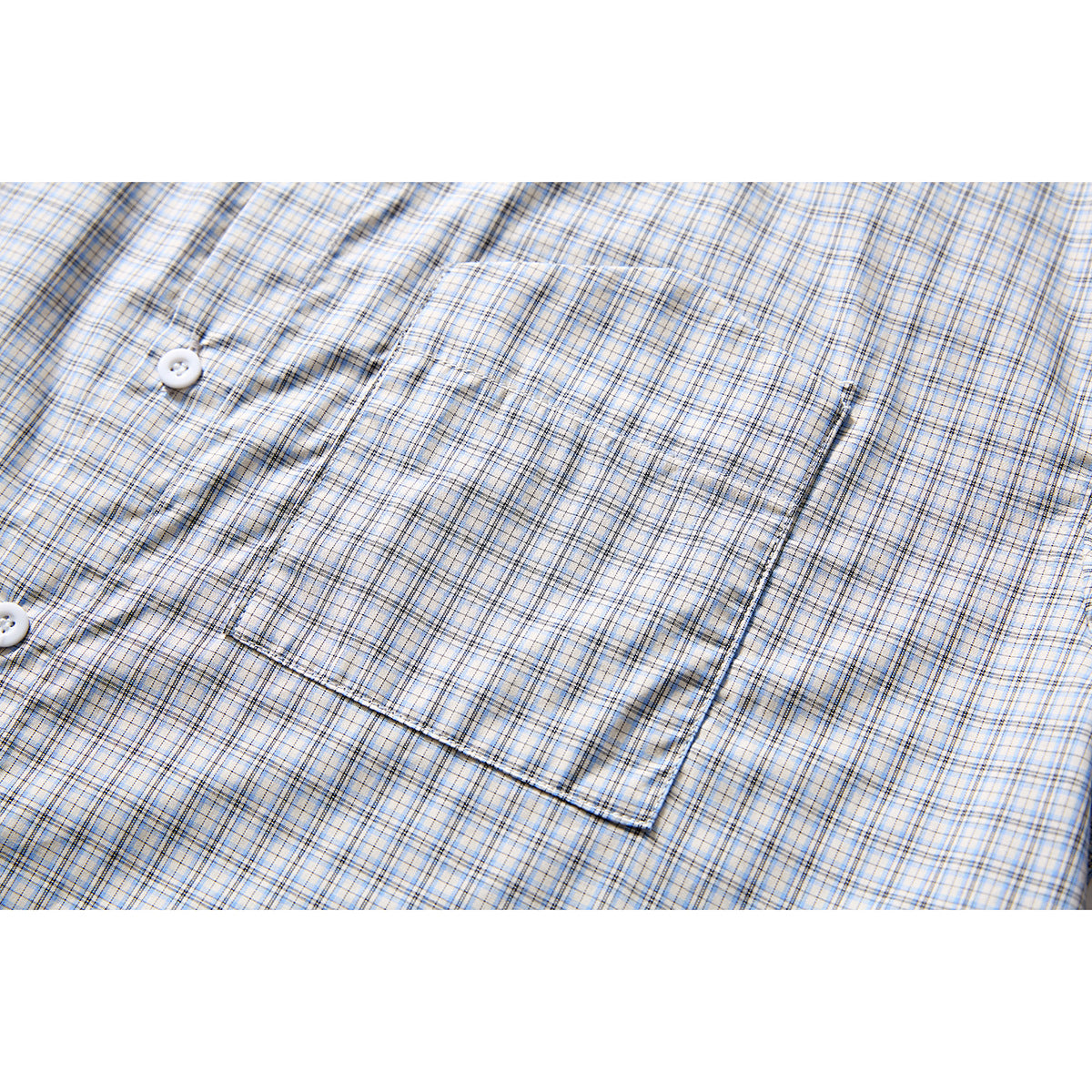 Close-up of a square chest pocket on a light plaid shirt, with white buttons visible at left.