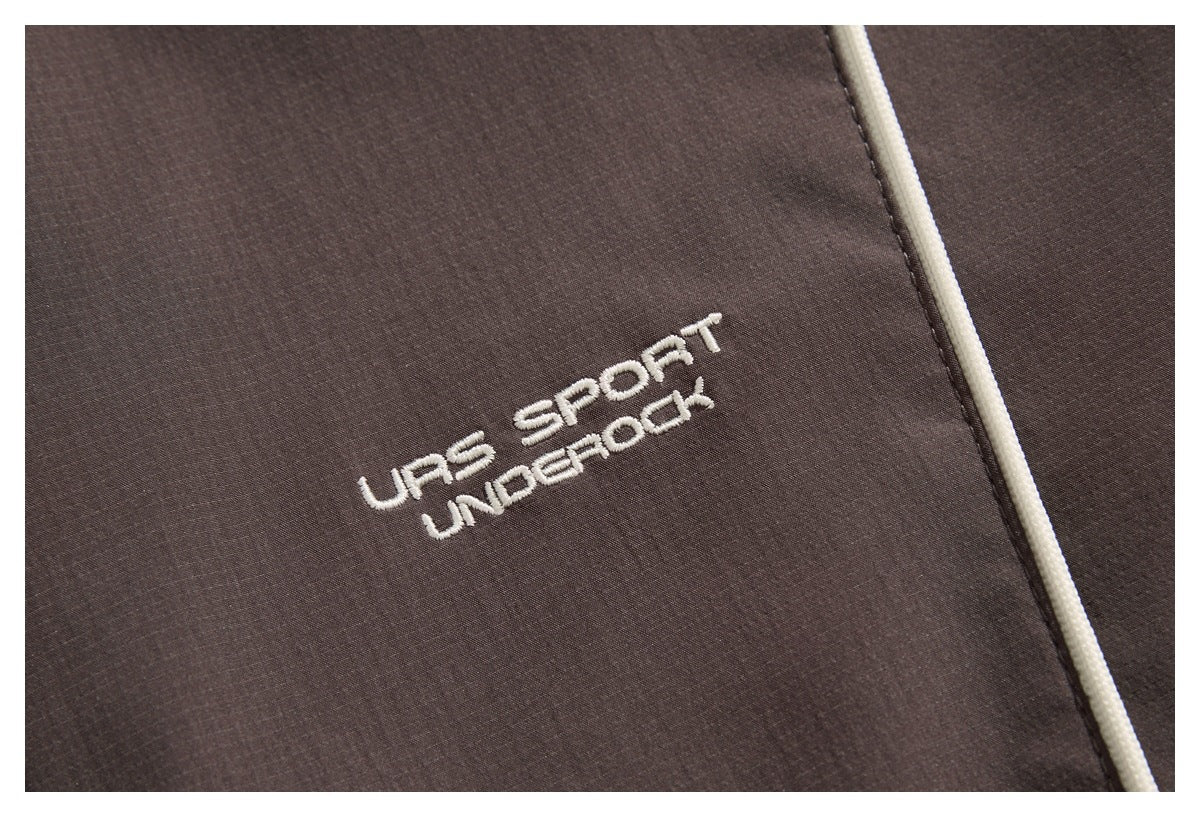 Close-up of dark brown fabric with white embroidered lettering and cream piping.
