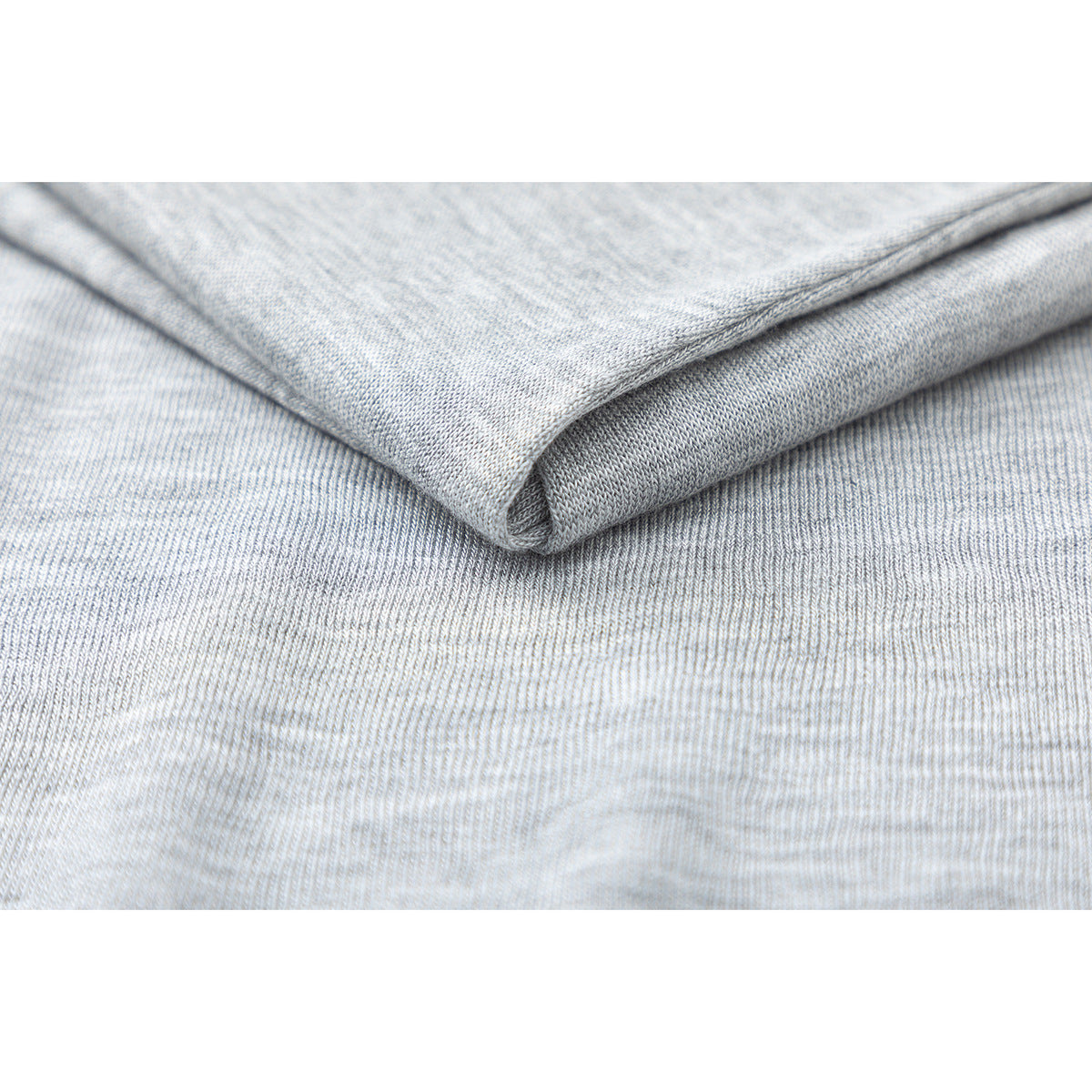 Close-up of light gray heather knit fabric folded to show its texture and edge.