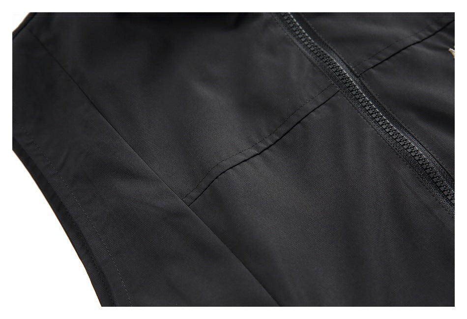 Close-up of the black vest's front zipper and curved panel stitching.