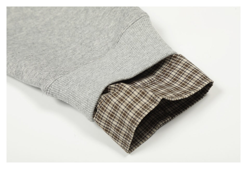 Close-up of a gray sweatshirt sleeve cuff with brown plaid fabric visible inside.