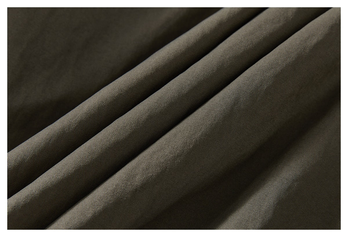 Close-up of olive-gray garment fabric arranged in soft folds, showing its fine woven texture.