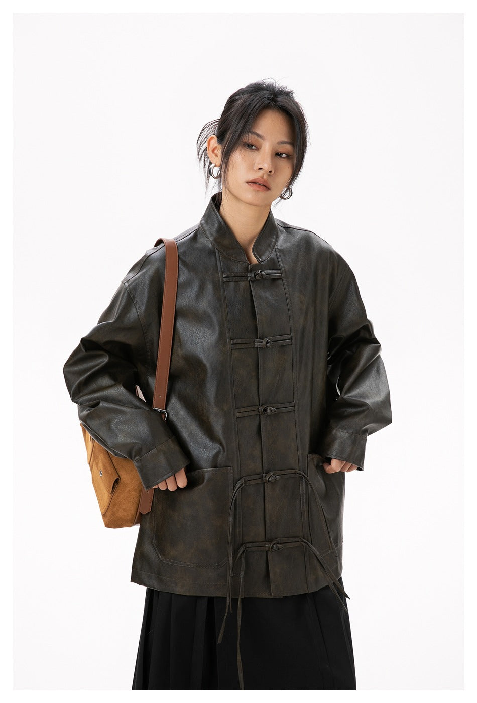 Front view of a model wearing a dark brown frog-button jacket with large pockets and a black skirt.