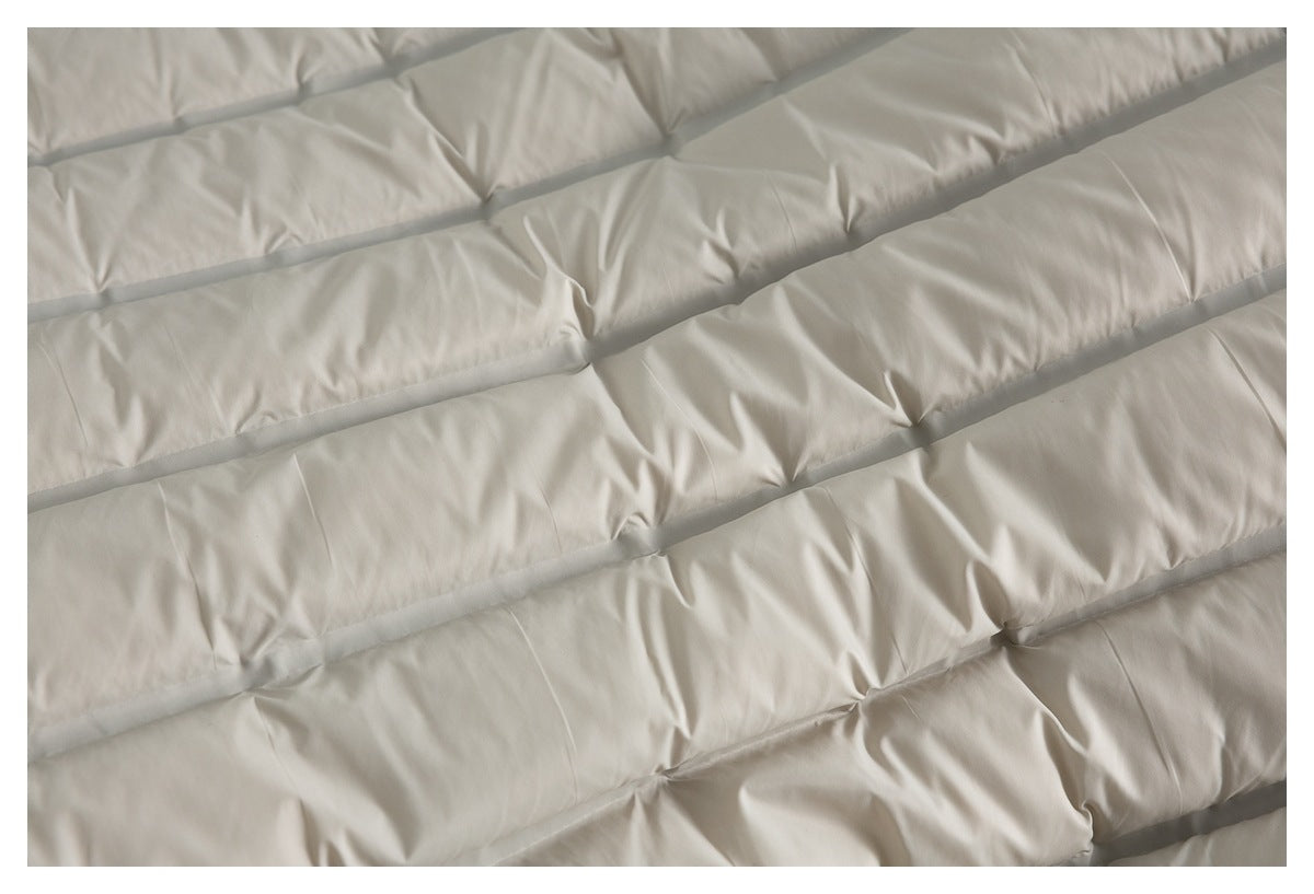 Close-up of a light beige padded jacket showing wide stitched quilted channels.