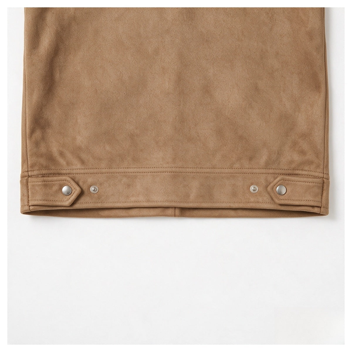 Close-up of the camel-brown jacket’s lower hem with snap-button tabs and visible stitching.