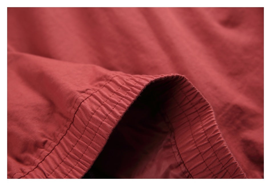 Close-up of the gathered elasticized edge and stitching on muted red fabric.