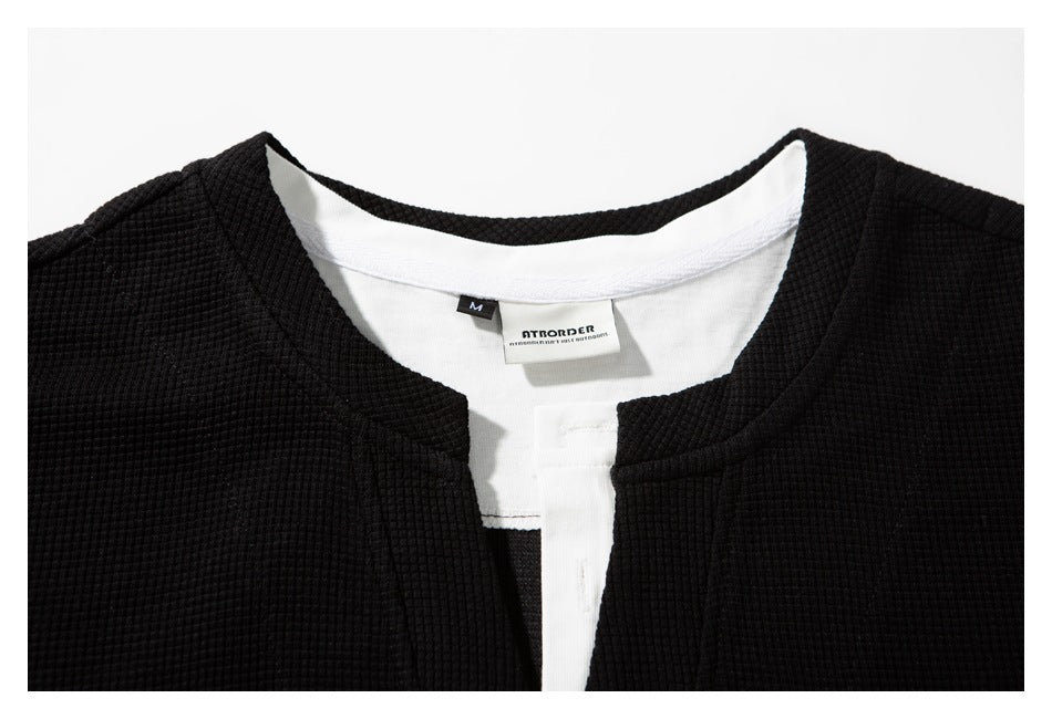Close-up of the black shirt's notched neckline, white inner facing, and sewn neck label.